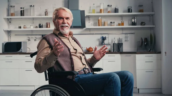 Pensionné handicapé souriant en parlant et assis en fauteuil roulant — Photo de stock