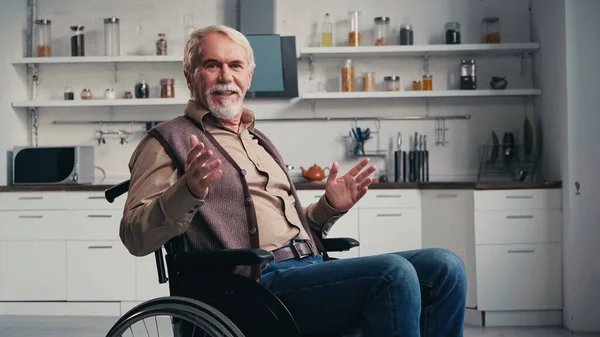 Handicapped pensioner smiling while talking and sitting in wheelchair — Stock Photo