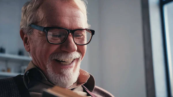 Close-up de feliz homem sênior em óculos livro de leitura em casa — Fotografia de Stock