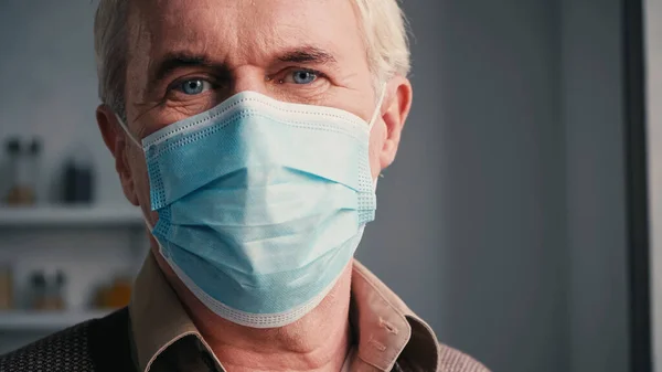Großaufnahme eines älteren Mannes mit blauen Augen in medizinischer Maske — Stockfoto