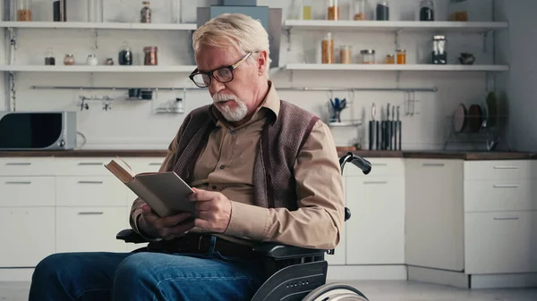 Инвалид старший человек в инвалидной коляске чтение книги — стоковое фото