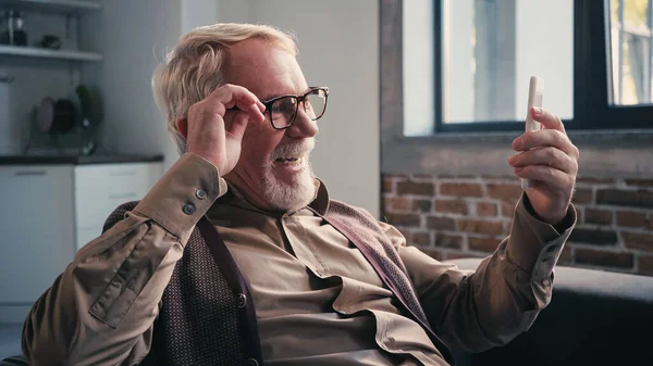Positive senior man in eyeglasses having video chat on smartphone — Stock Photo