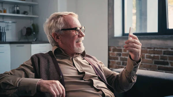 Homem sênior satisfeito em óculos ter chat de vídeo no smartphone — Fotografia de Stock