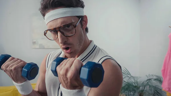 Athletic man exercising with dumbbells at home, retro sport concept — Stock Photo