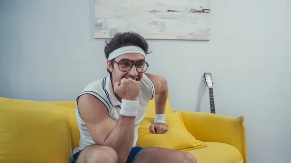 Deportista alegre en gafas mirando hacia otro lado en la sala de estar - foto de stock