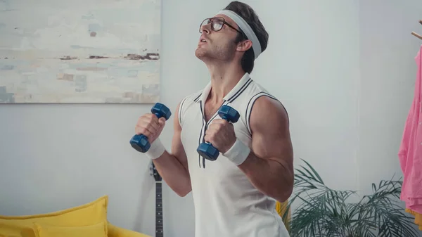 Sportsman in eyeglasses lifting dumbbells, retro sport concept — Stock Photo