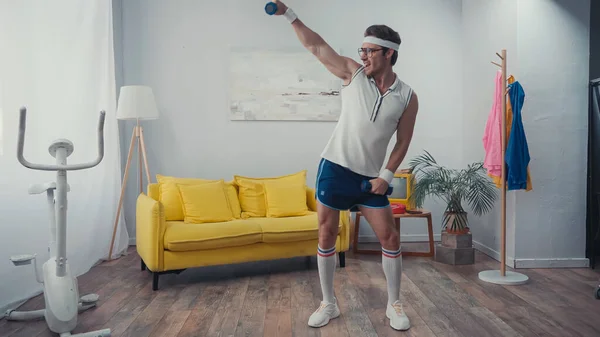 Deportista positivo levantando pesas y bailando en salón, concepto retro sport - foto de stock