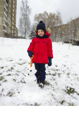 Evinin bahçesinde bir kış günü. O bir kardan adam yaptı. Oğlan parlak kırmızı bir ceket, mavi pantolon, eşarplı mavi bir şapka, eldivenler ve kışlık botlar giyiyor. Elinde turuncu bir kürek tutuyor. Bahçede kar var. Çocuk gülümsüyor..