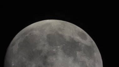 Close-up Moon on a dark night with clouds moving over it. Wobble image through a turbulent atmosphere