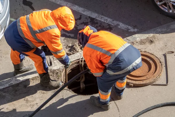 Arbeiter über der offenen Kanalluke reparieren Wasserversorgung — Stockfoto