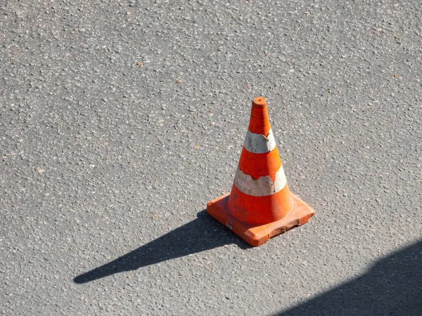 Old traffic cone standing on the asphalt road — Stock Photo, Image