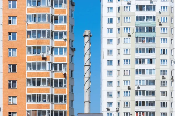 Cheminée tube contre un ciel bleu entouré d'immeubles d'appartements — Photo