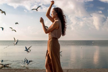 Güzel Asyalı Kadın Deniz kenarında martılarla poz veriyor.