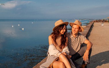 Çok ırklı bir çift deniz kıyısında Martı 'nın arka planında tatilin tadını çıkarıyor..