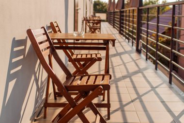 Modern balkonda güneş ışığı, masa ve sandalyeler. Güneş ışığı ve gölgede balkon manzarası