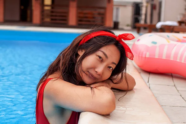 酒店游泳池里穿着雅致红色泳衣的性感亚洲女人放松一下 — 图库照片