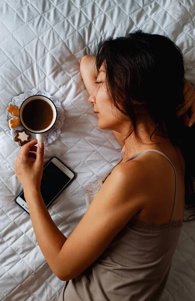 전화기와 커피로 침대에 아시아 — 스톡 사진