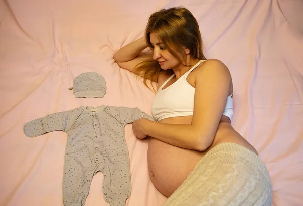 Schwangere Weißer Unterwäsche Mit Babykleidung Auf Dem Bett — Stockfoto