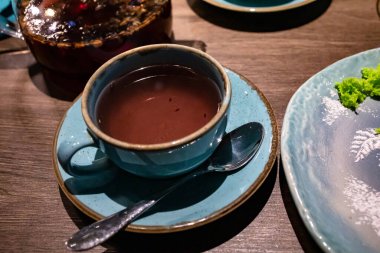 Tahta masadaki siyah çaylı mavi fincana yaklaş.