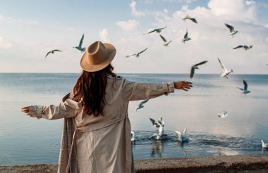 Sahilde denize karşı duran kadının arka görüntüsü.