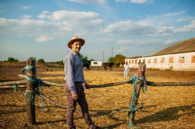 Aile Çiftliği 'nin dışında dikilen Olgun Erkek Çiftçi Portresi.