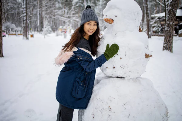 Νεαρή Ασιάτισσα Γυναίκα Παίζει Κοντά Μεγάλο Χιονάνθρωπο Στο Χειμερινό Πάρκο — Φωτογραφία Αρχείου