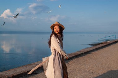 Güzel Asyalı Kadın Deniz kenarında martılarla poz veriyor.