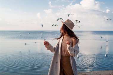 Güzel Asyalı Kadın Deniz kenarında martılarla poz veriyor.