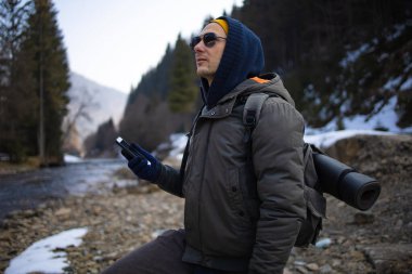 Kışlık Giyimde Genç Erkek Sırt Çantası Kış Ormanında Akıllı Telefon Kullanıyor
