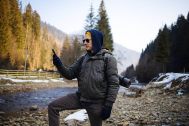 Kışlık Giyimde Genç Erkek Sırt Çantası Kış Ormanında Akıllı Telefon Kullanıyor