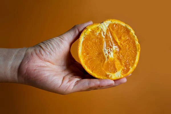 Tangan Wanita Memegang Setengah Oranye Pada Latar Belakang Oranye Kuning — Stok Foto
