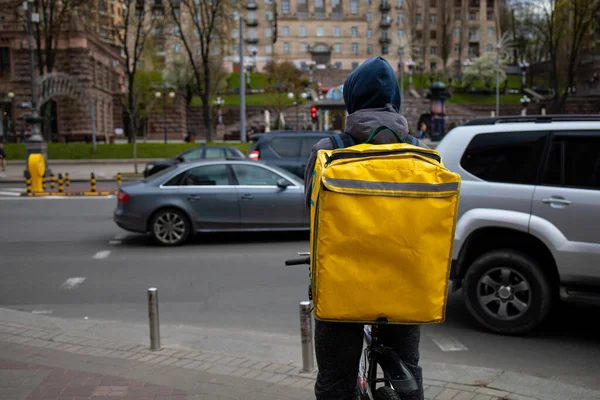 Food Delivery Man On Bike With Yellow Bag Drive In Urban City