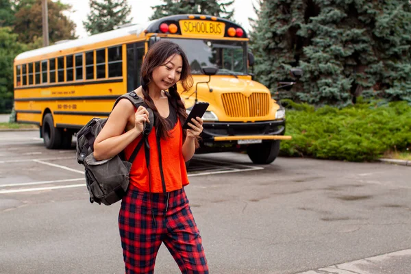 Asyalı Genç Kız Sırt Çantasıyla Büyük Sarı Bir Okul Servisinin — Stok fotoğraf