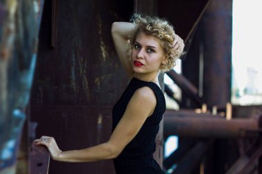 Eski fabrikadaki zarif siyah elbiseli, mavi gözlü, seksi moda modelinin moda çekimi.