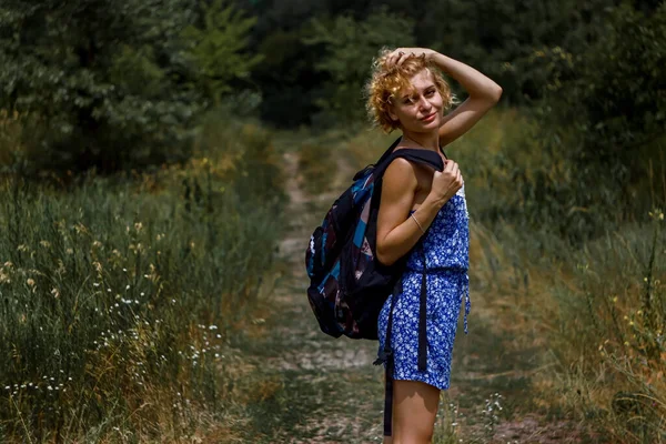 女人穿着衣服 背着背包站在绿地中间散步 — 图库照片