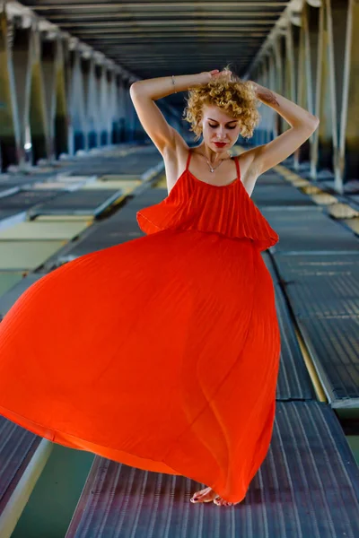 美丽的金发美女 红衣卷曲的金发女子在桥下跳舞 — 图库照片