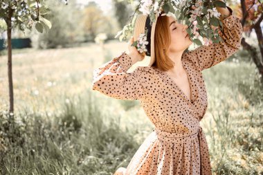 Çimenlerde oturan çekici, şehvetli genç kadın. Karahindiba desenli.