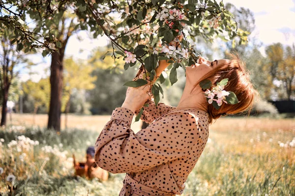 一位红头发的年轻白人妇女站在一棵开花的苹果树旁边 — 图库照片
