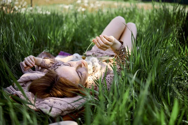迷人的年轻女子与蒲公英坐在草地上 — 图库照片