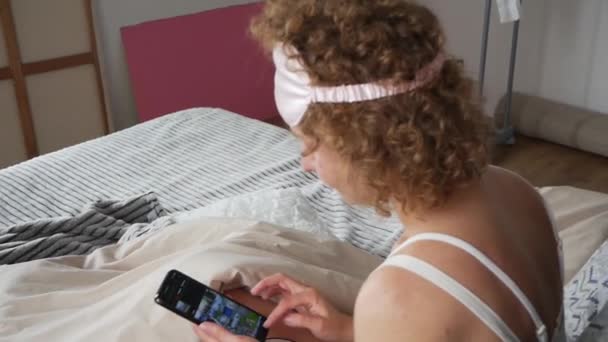 Blondynka Pije Filiżankę Kawy Patrzy Telefon Wczesnym Rankiem Łóżku — Wideo stockowe