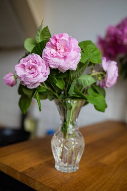 Tahta bir masadaki yumuşak güller, cam bir vazo.. 