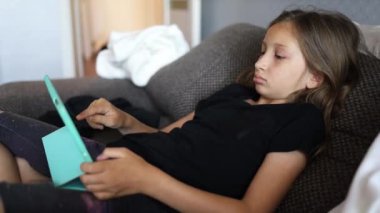 Baba ve kızı Dijital tablet kullanarak koltukta oturuyorlar.