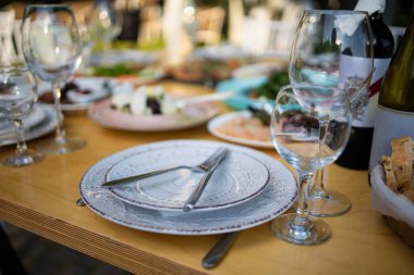 Tabaklar, aperatifler, şarap kadehleri ile servis edilen ziyafet masası.