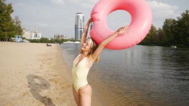 Genç bir kadın kumsalda şişme yüzükle eğleniyor..