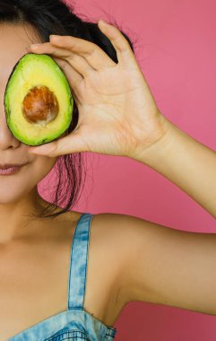 Yarı Pembe Arkaplanda Avokado Tutan Güzel Asyalı Kadın.