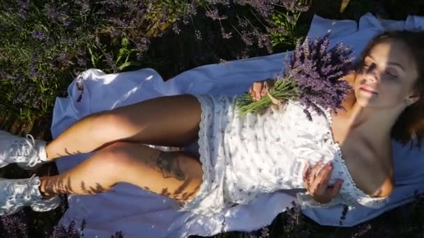 夏の日にラベンダー畑でリラックスする若い美しいブロンドの女性 — ストック動画