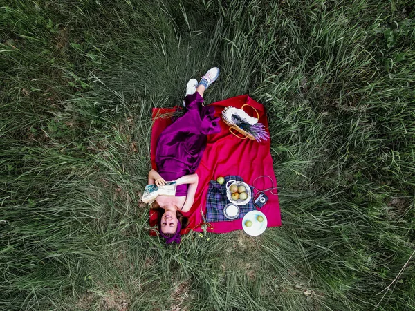 一个女人躺在草地上 提着一个野餐篮 — 图库照片