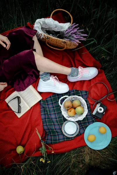 Woman Lying Outdoors At Park With Picnic Basket Eatting Apple
