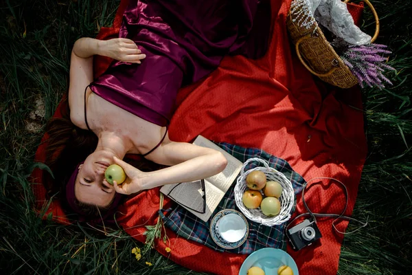 妇女躺在公园的室外 带着野餐篮吃苹果 — 图库照片