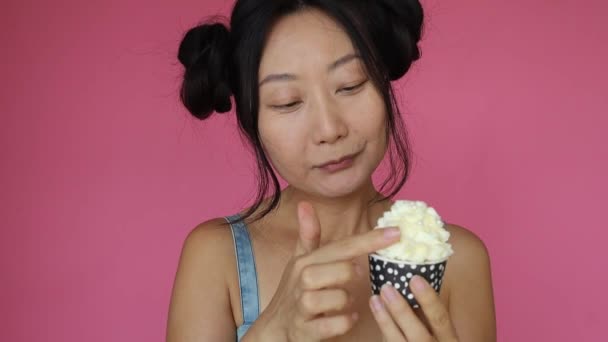 Cute Asian Girl Licking Cupcake Cream Pink Background — Video Stock
